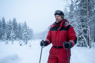 Aventurier en combinaison de ski rouge dans la forêt enneigée de Laponie finlandaise