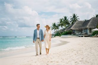 Couple élégant en voyage sur une plage de sable blanc