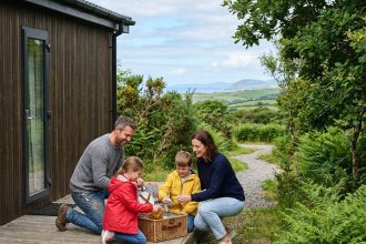 Famille souriante déballant un pique-nique devant un mobile home en Bretagne